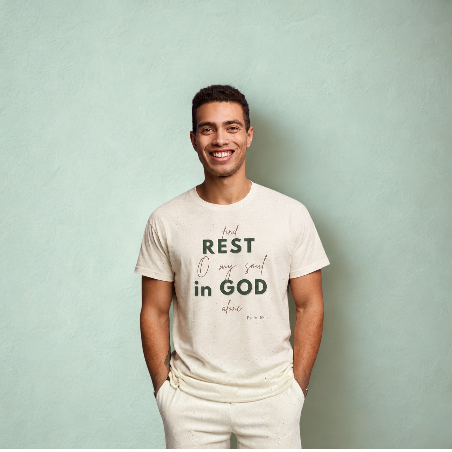 Front view of a man modeling a cream speckled Christian T-shirt with the inspirational Bible verse message “Find Rest O My Soul in God Alone” from Psalm 62:5